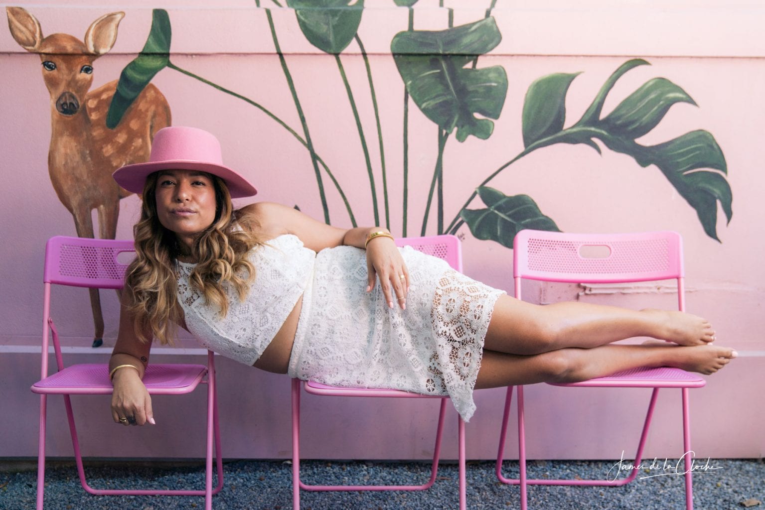 Girl in pink hat laying on pink chairs
